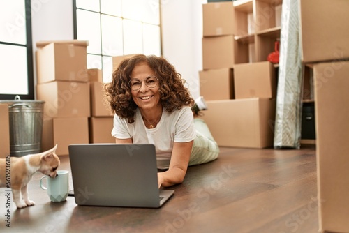 Middle age hispanic woman smiling confident using laptop at new home