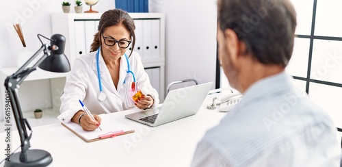 Middle age man and woman wearing doctor uniform prescribe pills at clinic