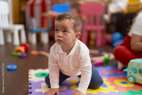 Adorable toddler lying on floor with relaxed expression at kindergarten