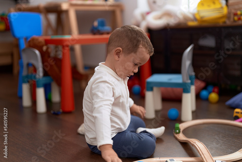 Adorable toddler playing with cars toy sitting on floor at kindergarten