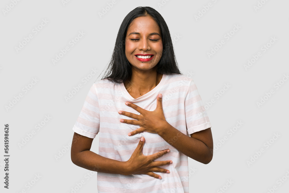 Young Indian woman cut out isolated on white background laughs happily and has fun keeping hands on stomach. Young Indian woman cut out isolated on white background laughs happily and has fun keeping hands on stomach.