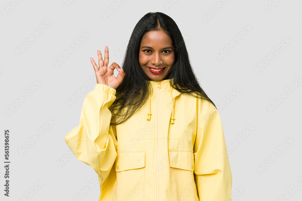 Young Indian woman cut out isolated on white background winks an eye and holds an okay gesture with hand. Young Indian woman cut out isolated on white background winks an eye and holds an okay gesture with hand.
