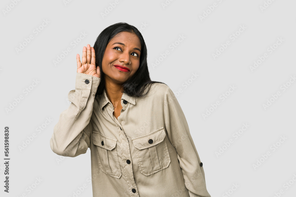 Young Indian woman cut out isolated on white background trying to listening a gossip. Young Indian woman cut out isolated on white background trying to listening a gossip.
