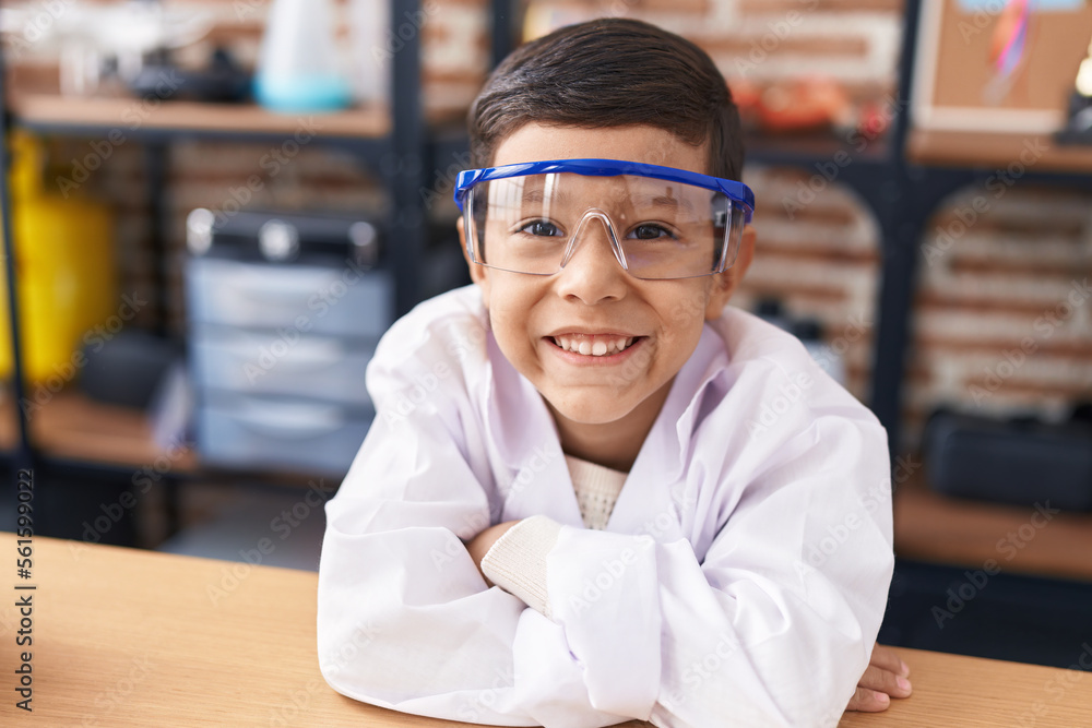 Adorable hispanic boy student leaning on table with arms crossed gesture at laboratory classroom Adorable hispanic boy student leaning on table with arms crossed gesture at laboratory classroom