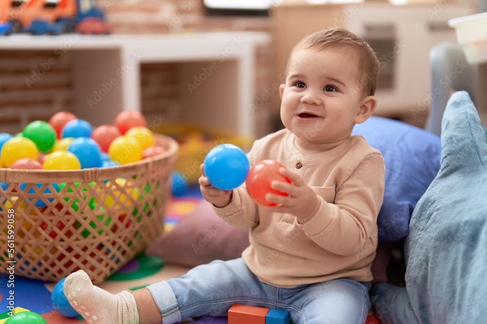 Adorable toddler playing with balls sitting on floor at kindergarten Adorable toddler playing with balls sitting on floor at kindergarten