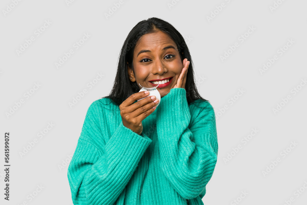 Young Indian woman holding a teeth whitener isolated on white background Young Indian woman holding a teeth whitener isolated on white background