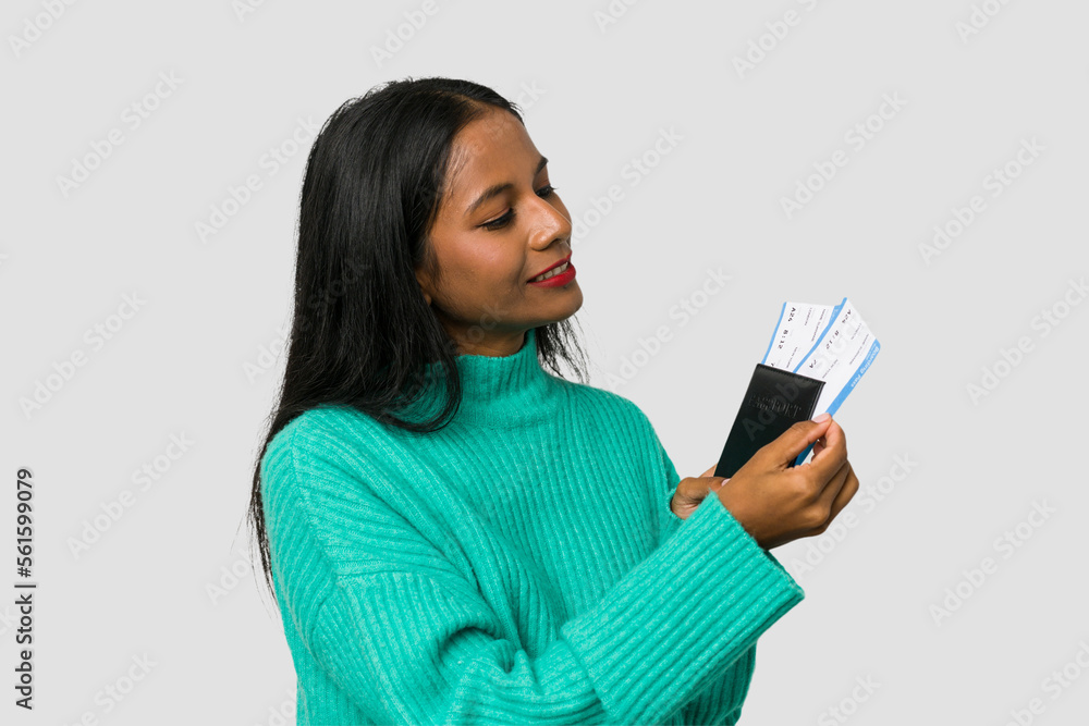 Young Indian woman holding a passport and flight tickets isolated on white background Young Indian woman holding a passport and flight tickets isolated on white background