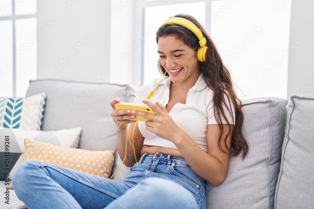 Young hispanic woman playing video game sitting on sofa at home Young hispanic woman playing video game sitting on sofa at home