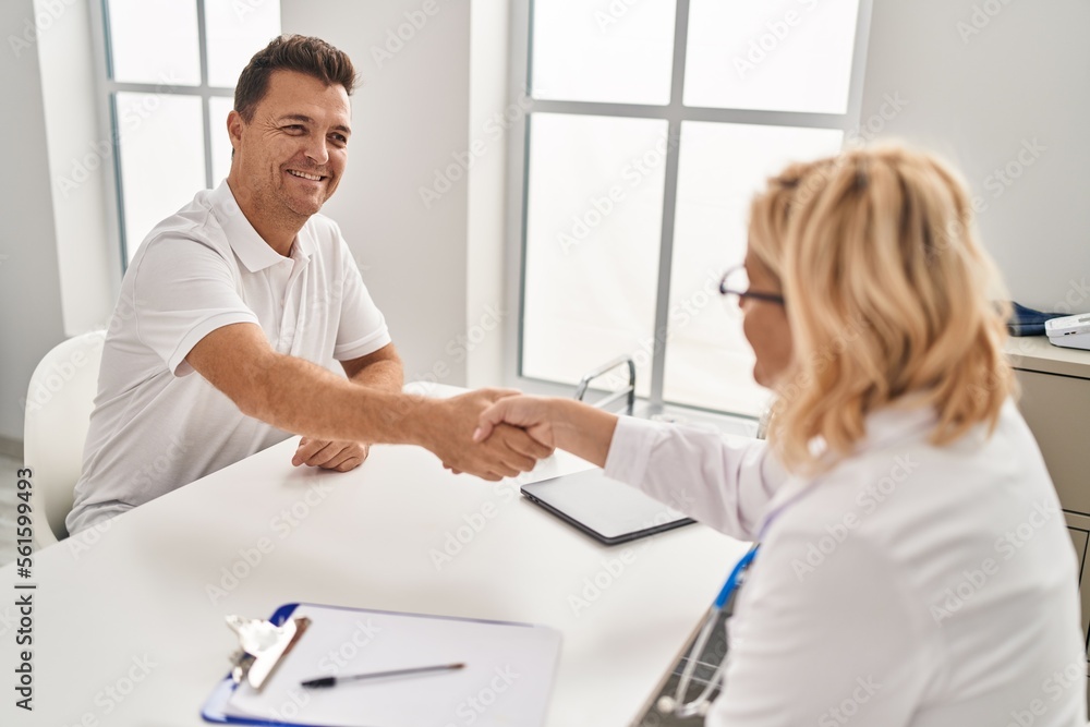 Middle age man and woman doctor and patient shake hands having medical consultation at clinic Middle age man and woman doctor and patient shake hands having medical consultation at clinic