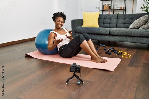 African american woman recording video sitting on yoga mat speaking at home