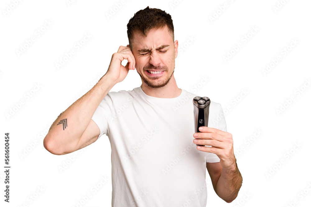Young man holding a shaving machine cut out isolated covering ears with hands. Young man holding a shaving machine cut out isolated covering ears with hands.