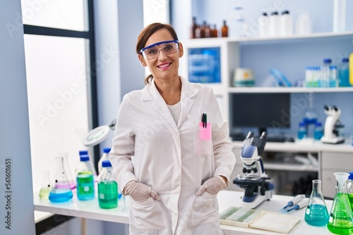 Middle age woman wearing scientist uniform standing at laboratory