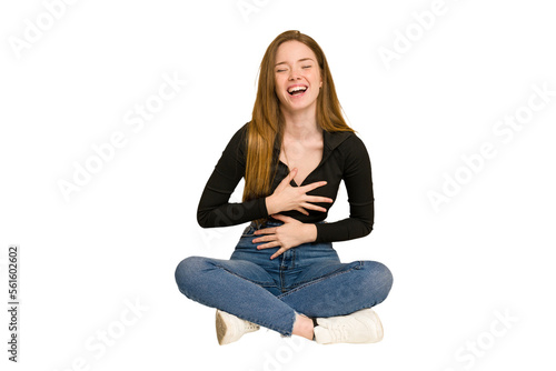 Young redhead woman sitting on the floor cut out isolated laughing and having fun.