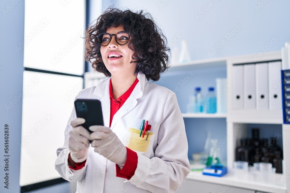 Young beautiful hispanic woman scientist smiling confident using smartphone at laboratory Young beautiful hispanic woman scientist smiling confident using smartphone at laboratory