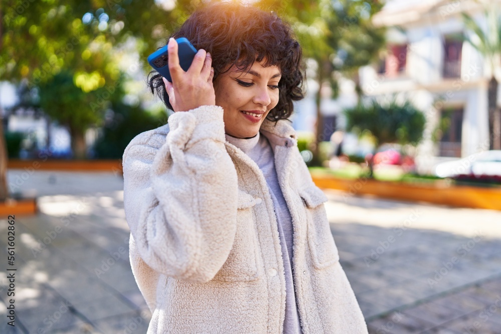 Fototapeta premium Young beautiful hispanic woman smiling confident listening audio message by the smartphone at park
