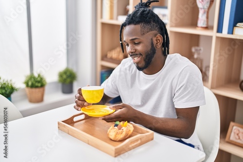 African american woman having breakfast sitting on table at home