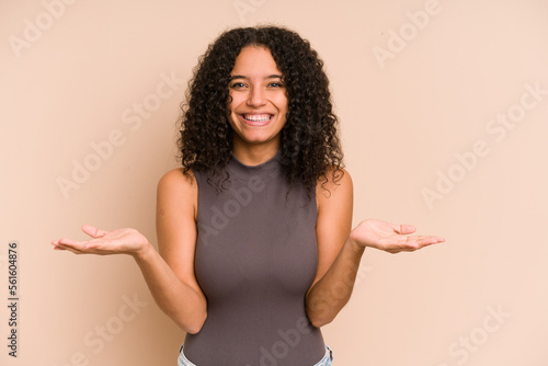 Billede på lærred Young african american curly woman isolated makes scale with arms, feels happy and confident