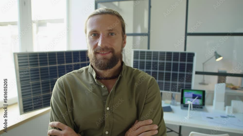 Portrait of male renewable energy developer looking at camera and smiling while posing with arms crossed in office Portrait of male renewable energy developer looking at camera and smiling while posing with arms crossed in office