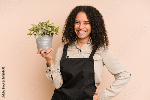 Foto Young african american gardener woman holding a plant isolated
