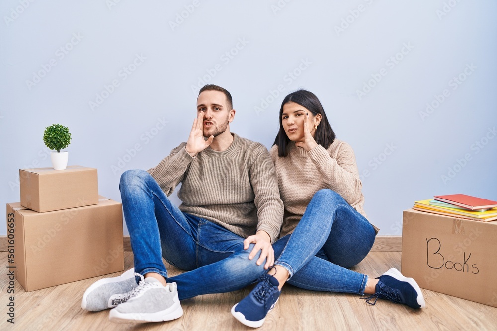 Young couple moving to a new home hand on mouth telling secret rumor, whispering malicious talk conversation Young couple moving to a new home hand on mouth telling secret rumor, whispering malicious talk conversation