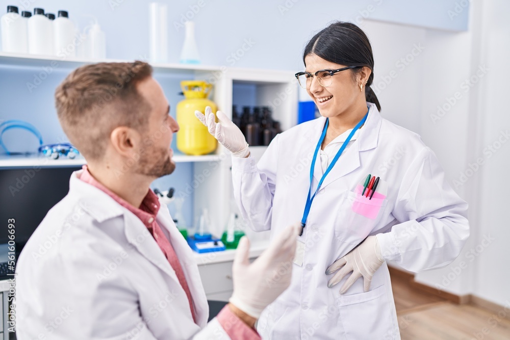 Man and woman wearing scientists uniform speaking at laboratory Man and woman wearing scientists uniform speaking at laboratory