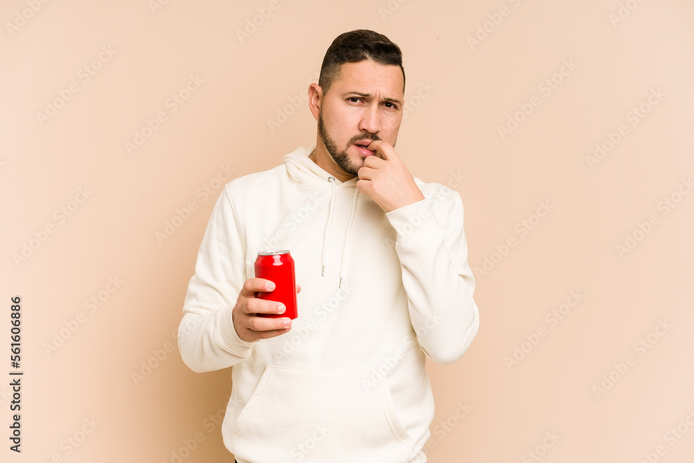 Young latin man holding a cola refreshment isolated relaxed thinking about something looking at a copy space. Young latin man holding a cola refreshment isolated relaxed thinking about something looking at a copy space.