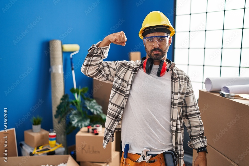 Young hispanic man with beard working at home renovation strong person showing arm muscle, confident and proud of power Young hispanic man with beard working at home renovation strong person showing arm muscle, confident and proud of power