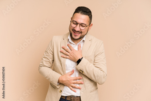Adult latin business man cut out isolated laughs happily and has fun keeping hands on stomach. © Asier