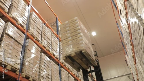 Loading and unloading goods in a logistics warehouse using a forklift. Boxes on a pallet are lifted onto racks