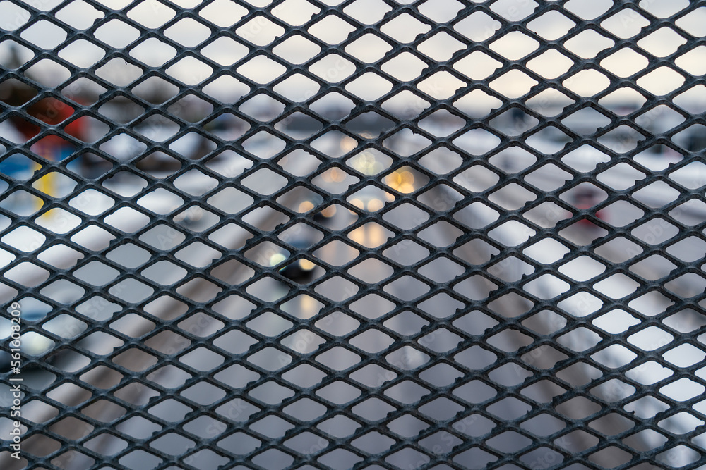 Metal bridge fence background with holes. In the background, a highway with moving cars Metal bridge fence background with holes. In the background, a highway with moving cars