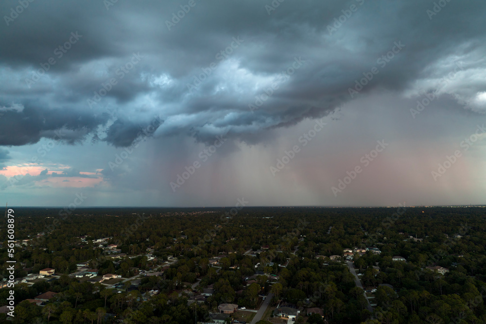 Fototapeta premium Dark stormy clouds forming on gloomy sky before heavy rainfall over suburban town area