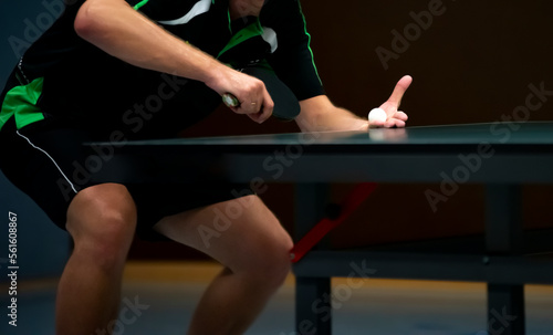 table tennis player serving, holding ball in his hand