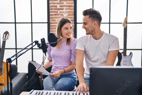 Man and woman musicians singing song playing piano at music studio