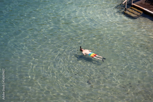 Aerial view to sea and man in scuba mask swimming in transparent water. Snorkeling and diving on shallow, beach vacation