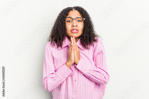 Young african american woman isolated on white background holding hands in pray near mouth, feels confident.