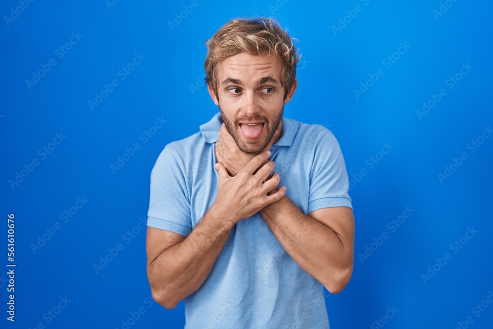 Caucasian man standing over blue background shouting suffocate because painful strangle. health problem. asphyxiate and suicide concept. Caucasian man standing over blue background shouting suffocate because painful strangle. health problem. asphyxiate and suicide concept.