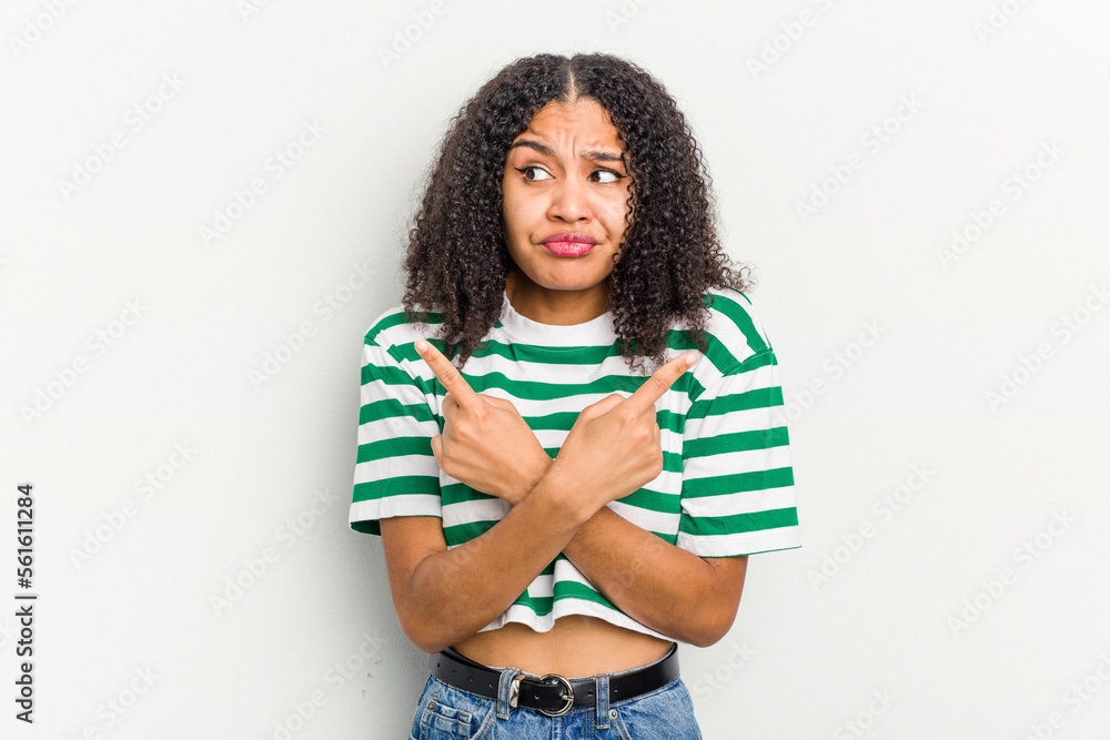 Young african american woman isolated on white background points sideways, is trying to choose between two options. Young african american woman isolated on white background points sideways, is trying to choose between two options.