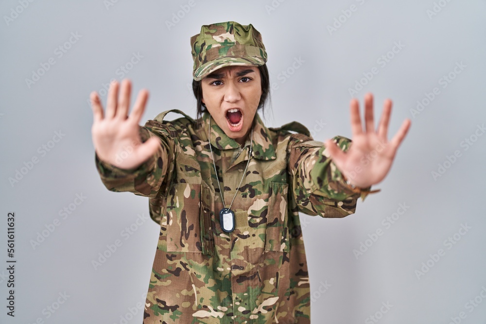 Young south asian woman wearing camouflage army uniform doing stop gesture with hands palms, angry and frustration expression Young south asian woman wearing camouflage army uniform doing stop gesture with hands palms, angry and frustration expression
