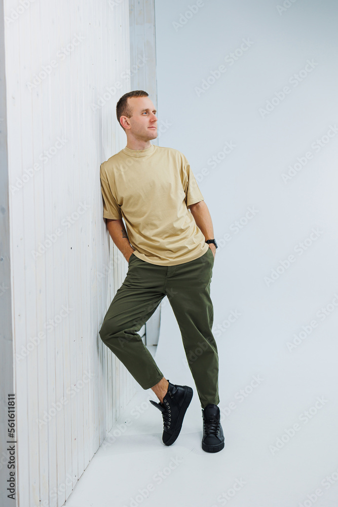 A young handsome man in casual clothes poses on a white background in the studio A young handsome man in casual clothes poses on a white background in the studio
