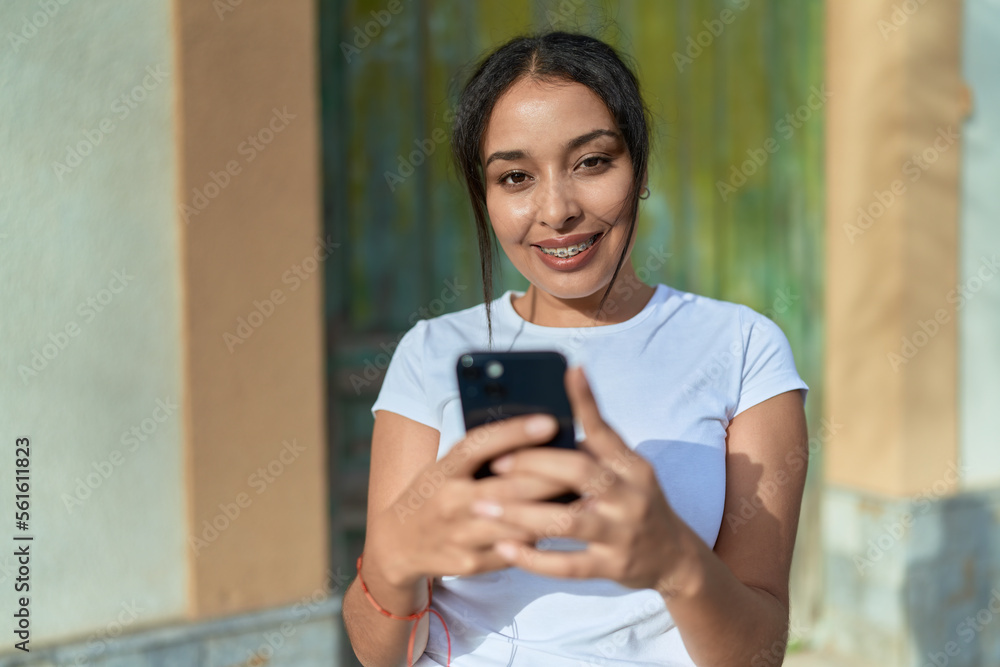 Young arab woman smiling confident using smartphone at street