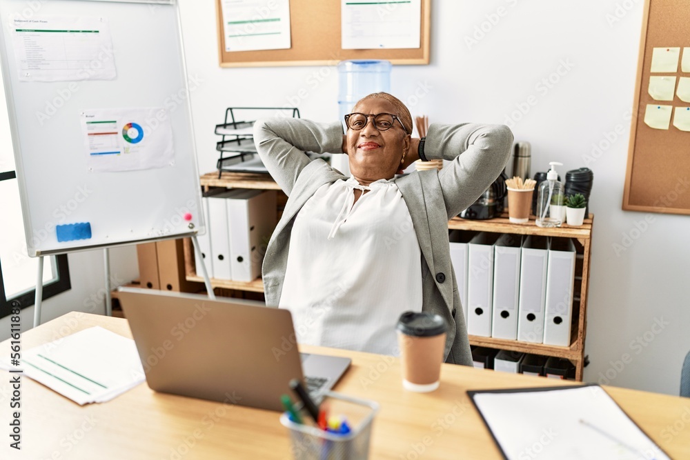 Senior african american woman business worker relaxed with hands on head at office