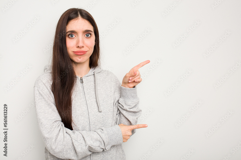Young caucasian woman isolated on white background shocked pointing with index fingers to a copy space. Young caucasian woman isolated on white background shocked pointing with index fingers to a copy space.