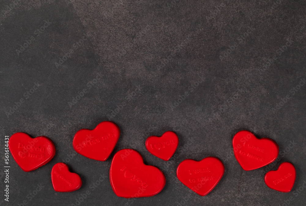 Jelly candies in the shape of a red heart with thematic inscriptions. Valentine's Day. Dark gray background. Copy space. Top view	