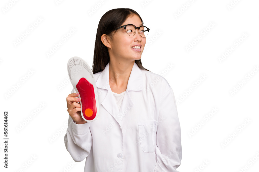 Young asian chiropodist holding a insoles for shoes isolated looks aside smiling, cheerful and pleasant. Young asian chiropodist holding a insoles for shoes isolated looks aside smiling, cheerful and pleasant.