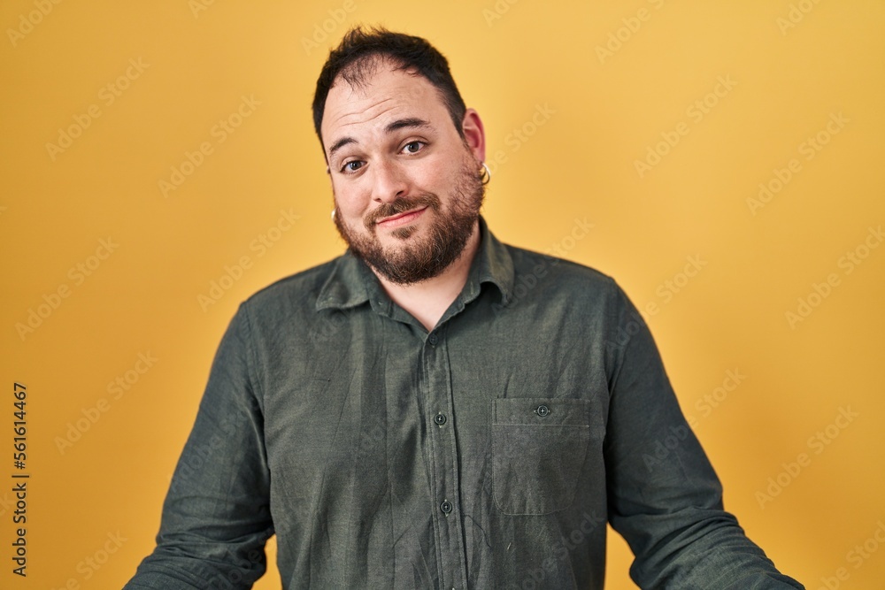 Plus size hispanic man with beard standing over yellow background smiling cheerful with open arms as friendly welcome, positive and confident greetings Plus size hispanic man with beard standing over yellow background smiling cheerful with open arms as friendly welcome, positive and confident greetings