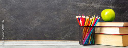 Back to school concept. School supplies on black board background.