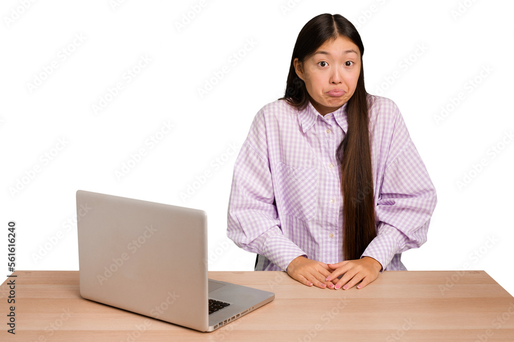 Φωτογραφία Young student asian woman in a workplace with a laptop isolated shrugs shoulders and open eyes confused