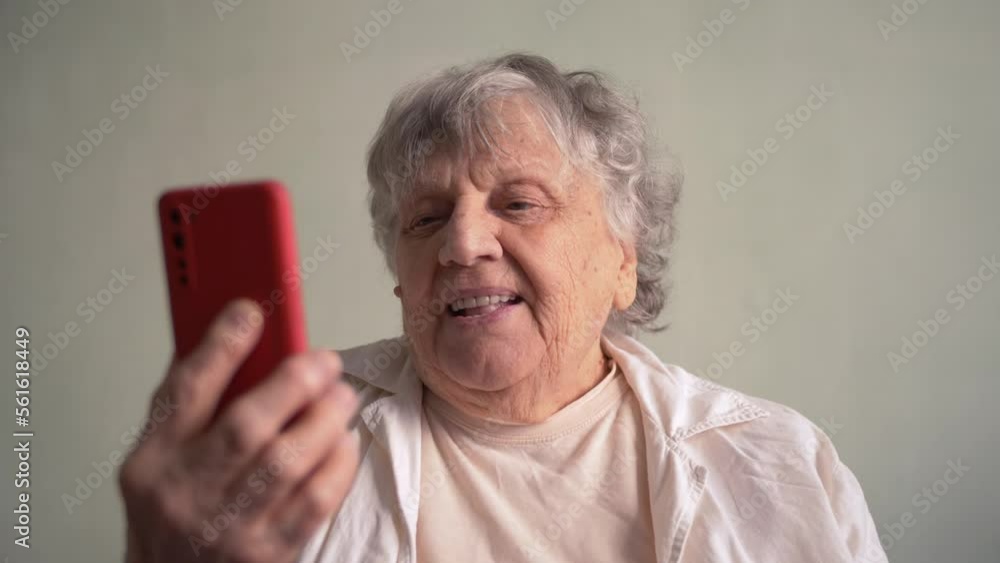 An elderly woman is talking online on a smartphone with her family. An elderly woman is talking online on a smartphone with her family.