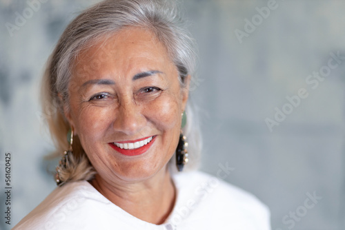 Gray-haired lady with bright makeup looks at the camera and laughs © Guzel