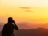 Photographer with tripod takes photos of a beautiful sunset